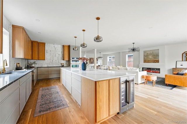 2391 Hudson St, Denver, CO 80207 - kitchen featuring beverage cooler, a sink, light wood-style floors, open floor plan, and backsplash