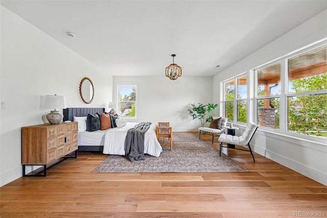 2391 Hudson St, Denver, CO 80207 - bedroom with multiple windows, a chandelier, light wood-style flooring, and baseboards