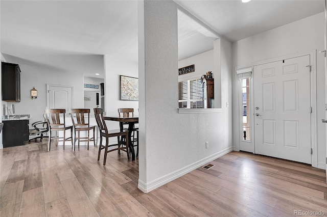 foyer entrance featuring light wood-style flooring, baseboards, and a textured wall