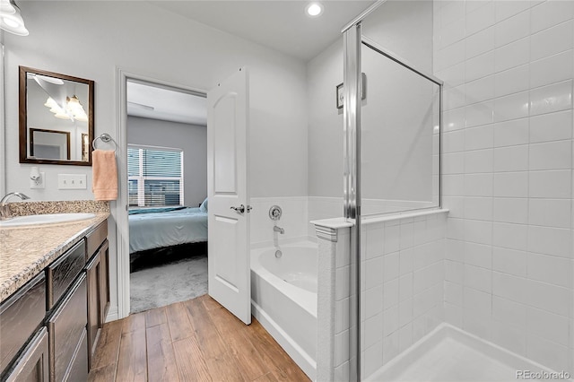 ensuite bathroom with wood finished floors, a stall shower, vanity, a bath, and recessed lighting