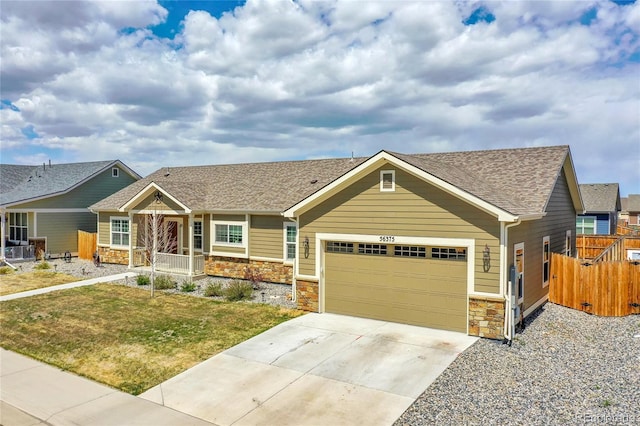 craftsman-style house featuring stone siding, an attached garage, concrete driveway, and a shingled roof
