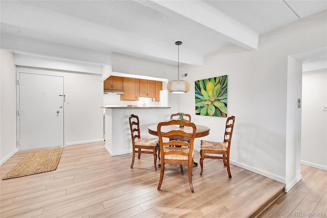 dining space with baseboards, beam ceiling, and light wood-style flooring