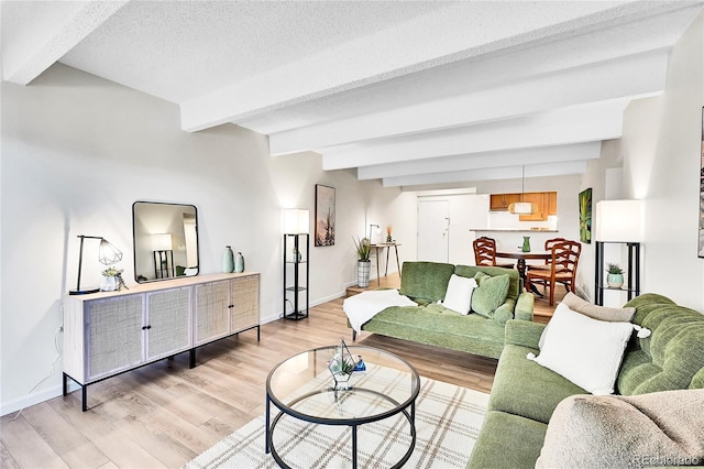 living area featuring light wood-type flooring, beamed ceiling, baseboards, and a textured ceiling