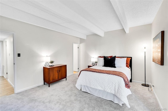 carpeted bedroom with beam ceiling, baseboards, and a textured ceiling