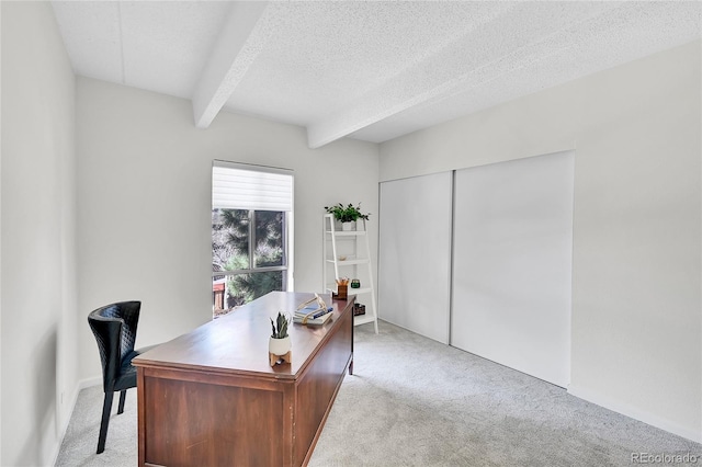 home office with beamed ceiling, light colored carpet, and a textured ceiling