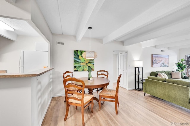 dining area with beam ceiling, light wood-style flooring, and baseboards