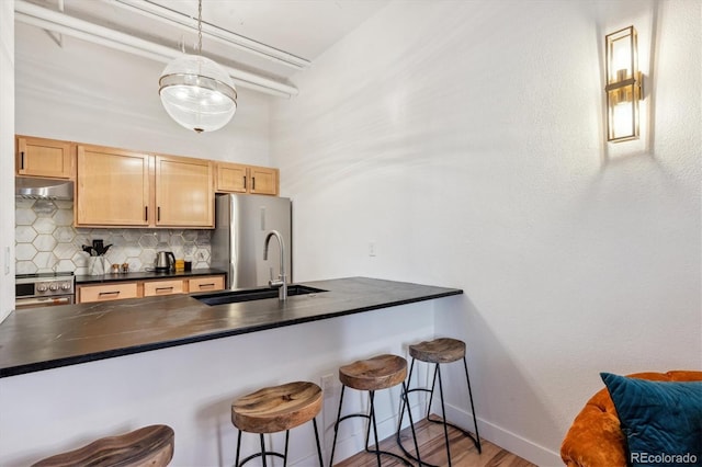 kitchen with tasteful backsplash, a kitchen breakfast bar, stainless steel appliances, hardwood / wood-style floors, and decorative light fixtures