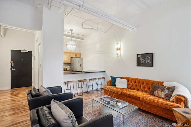 living room with light hardwood / wood-style flooring, a towering ceiling, and sink