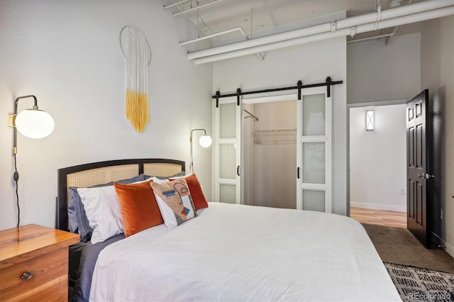 bedroom with a closet, carpet flooring, a barn door, a walk in closet, and a high ceiling