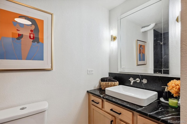 bathroom featuring vanity, toilet, and tasteful backsplash