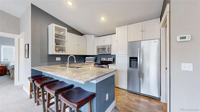 18274 W 58th Pl Unit 37, Golden, CO 80403 - kitchen with stainless steel appliances, a breakfast bar, lofted ceiling, light stone countertops, and glass insert cabinets