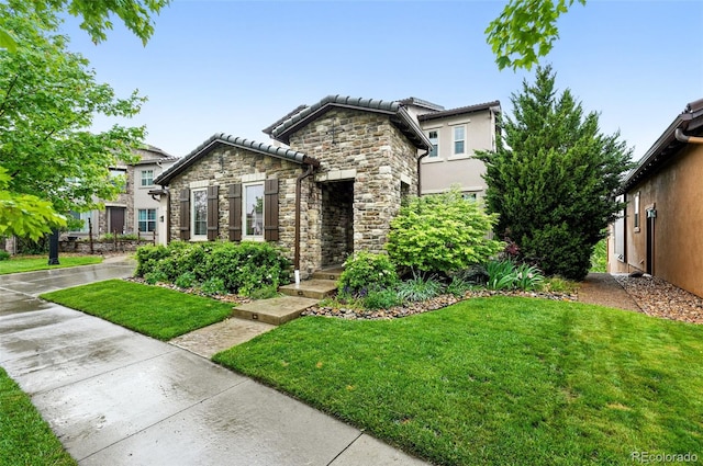 15377 W Iliff Dr, Denver, CO 80228 - view of front of home with stone siding, a front lawn, a tiled roof, and stucco siding