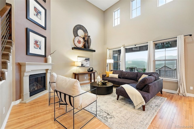 15377 W Iliff Dr, Denver, CO 80228 - living room with a glass covered fireplace, baseboards, wood-type flooring, a high ceiling, and a water view
