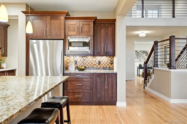 15377 W Iliff Dr, Denver, CO 80228 - kitchen featuring appliances with stainless steel finishes, baseboards, light wood-style floors, and tasteful backsplash