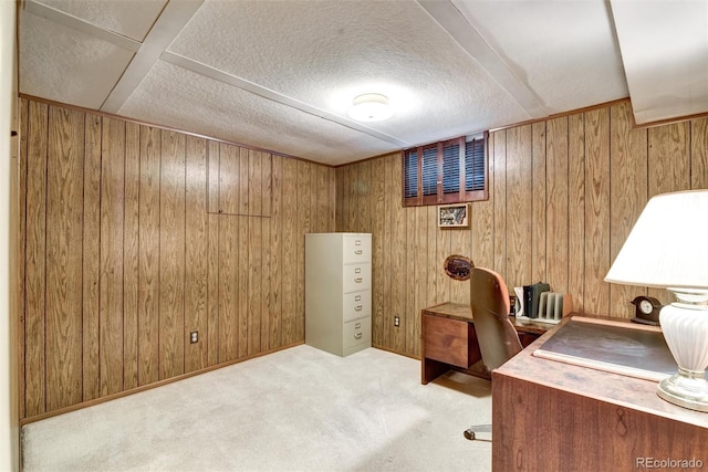 office area with light colored carpet, a textured ceiling, and wood walls