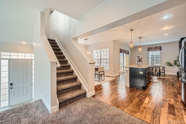 entrance foyer with stairs, dark wood-style floors, and a healthy amount of sunlight