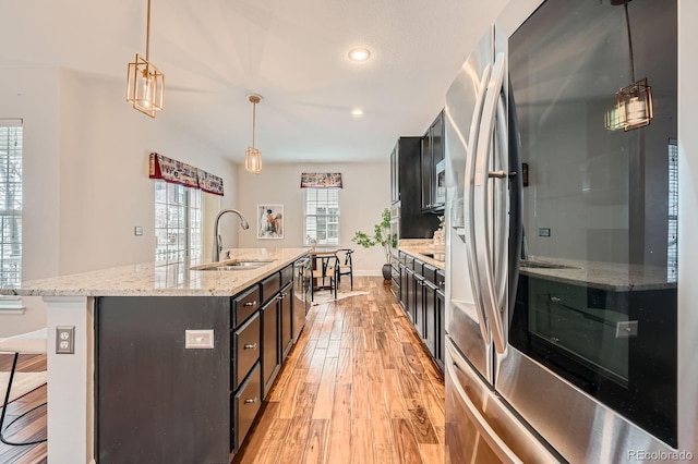 kitchen featuring an island with sink, light wood-style flooring, decorative light fixtures, smart refrigerator, and a sink