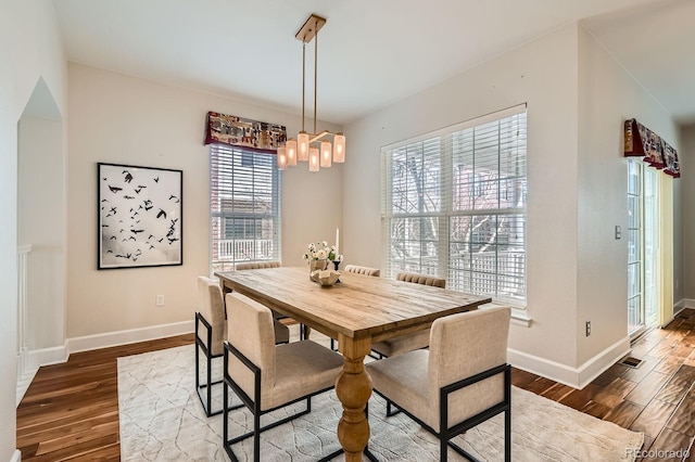 dining room with a notable chandelier, baseboards, and wood finished floors