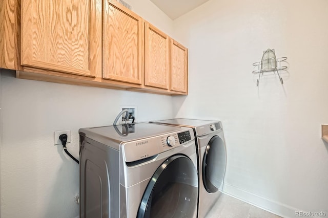 clothes washing area featuring washer and dryer, cabinet space, and baseboards