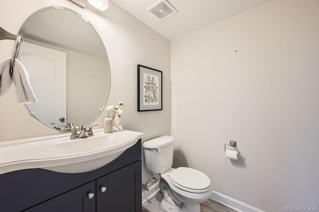 bathroom with baseboards, visible vents, vanity, and toilet