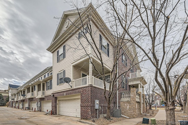 view of building exterior featuring cooling unit, driveway, and an attached garage