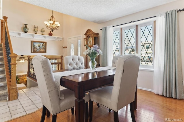 dining space with light wood-style floors, a notable chandelier, a textured ceiling, and a wealth of natural light