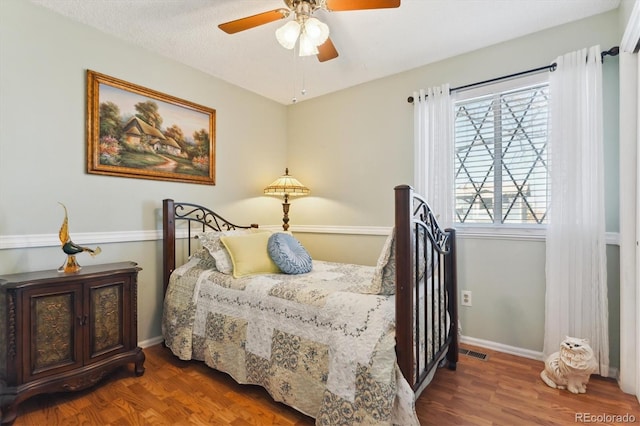 bedroom with a ceiling fan, wood finished floors, visible vents, and baseboards