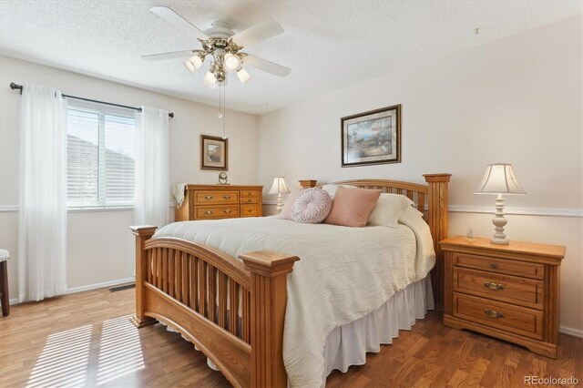 bedroom with a textured ceiling, a ceiling fan, and wood finished floors