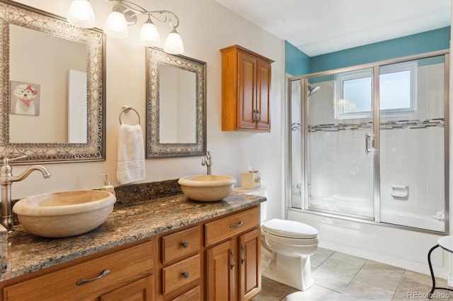 full bathroom with enclosed tub / shower combo, a sink, toilet, and double vanity