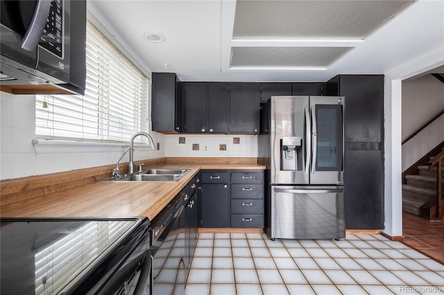 kitchen featuring wood counters, black / electric stove, stainless steel refrigerator with ice dispenser, and sink