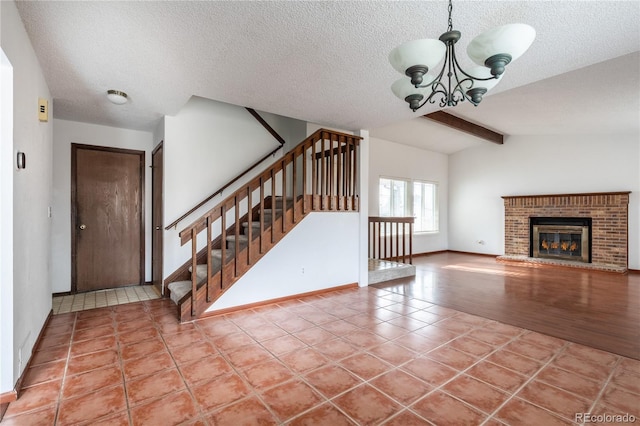 unfurnished living room featuring a textured ceiling, an inviting chandelier, vaulted ceiling with beams, a brick fireplace, and light tile patterned floors