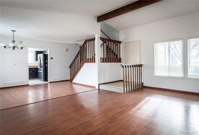 unfurnished living room with hardwood / wood-style floors, a chandelier, and vaulted ceiling with beams