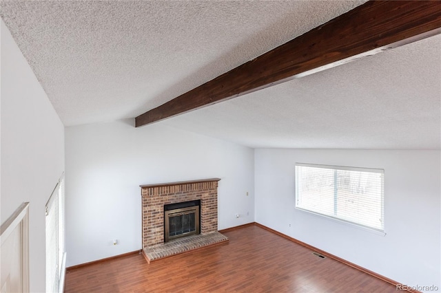 unfurnished living room with hardwood / wood-style flooring, a textured ceiling, vaulted ceiling with beams, and a fireplace