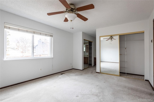 unfurnished bedroom featuring ceiling fan, light colored carpet, a closet, and a textured ceiling