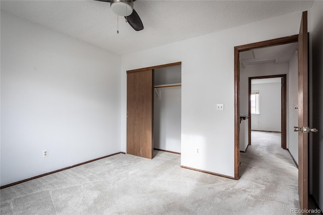 unfurnished bedroom featuring light carpet, ceiling fan, a closet, and a textured ceiling