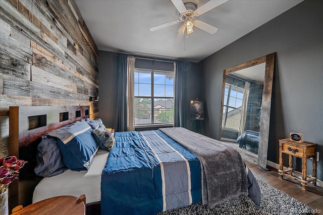 7413 S Quail Cir Unit 1435, Littleton, CO 80127 - bedroom featuring wood walls, wood finished floors, a ceiling fan, and an accent wall