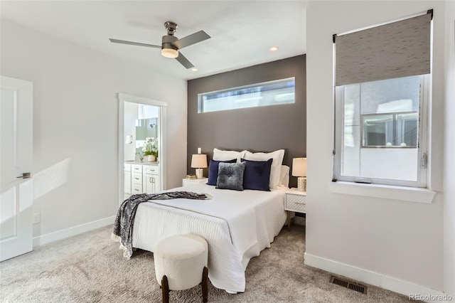 bedroom with ceiling fan, ensuite bathroom, and light carpet