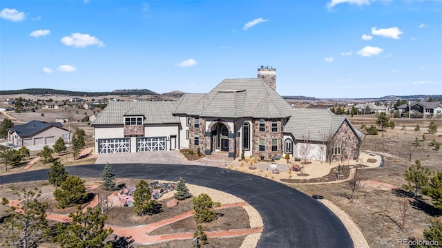 french country home featuring a garage, stone siding, driveway, and a tiled roof