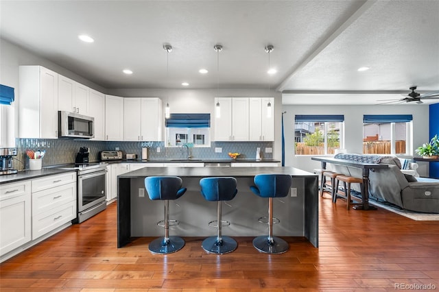 1353 Quaker St, Golden, CO 80401 - kitchen featuring appliances with stainless steel finishes, a kitchen breakfast bar, open floor plan, dark countertops, and recessed lighting