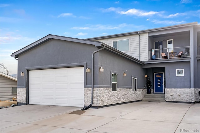 1353 Quaker St, Golden, CO 80401 - view of front of home featuring stone siding, concrete driveway, an attached garage, a balcony, and entry steps