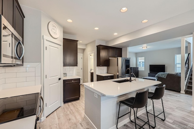668 Sage Forest Ln, Monument, CO 80132 - kitchen with appliances with stainless steel finishes, a sink, light wood-style floors, open floor plan, and dark brown cabinetry