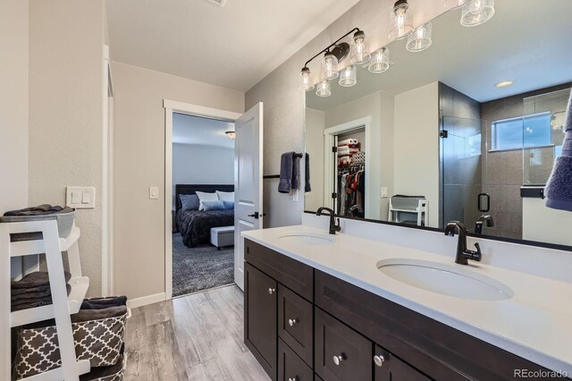 668 Sage Forest Ln, Monument, CO 80132 - ensuite bathroom with a shower stall, wood finished floors, double vanity, a spacious closet, and baseboards