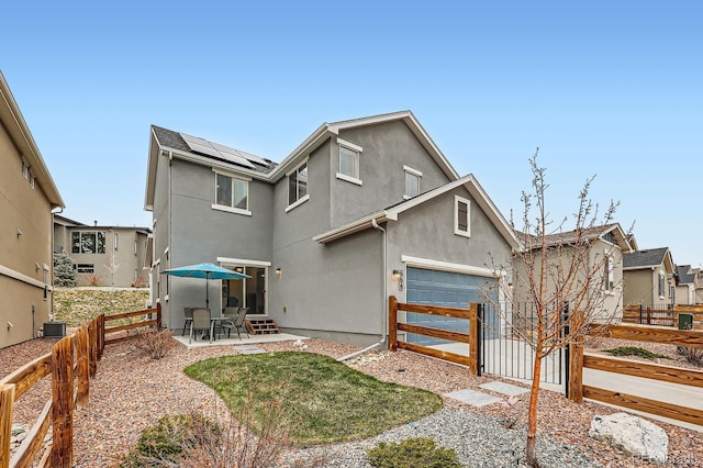 668 Sage Forest Ln, Monument, CO 80132 - back of house with solar panels, stucco siding, a gate, a garage, and a patio