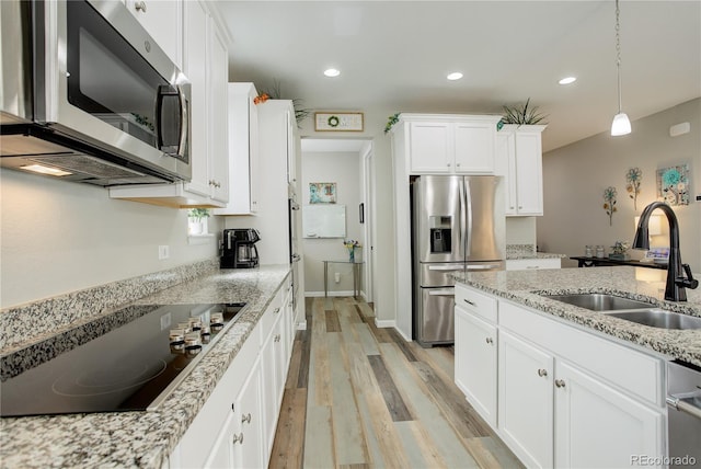kitchen featuring appliances with stainless steel finishes, a sink, light wood finished floors, white cabinets, and recessed lighting