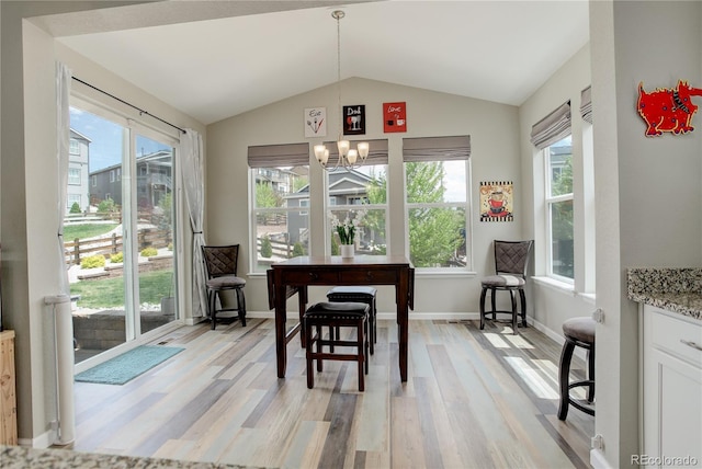 dining area featuring plenty of natural light, light wood-type flooring, a chandelier, vaulted ceiling, and baseboards