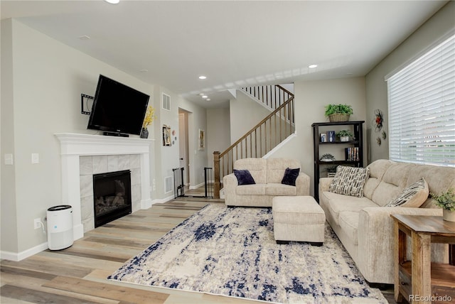 living area featuring wood finished floors, recessed lighting, stairs, baseboards, and a fireplace