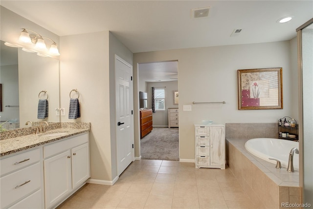 full bath featuring baseboards, vanity, tile patterned flooring, and a garden tub