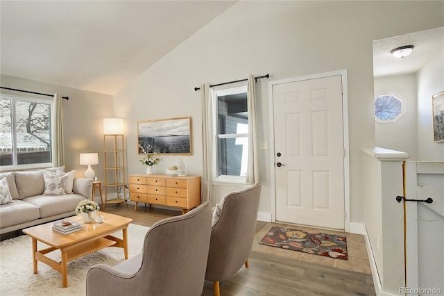 living room with lofted ceiling, a wealth of natural light, and light wood-type flooring