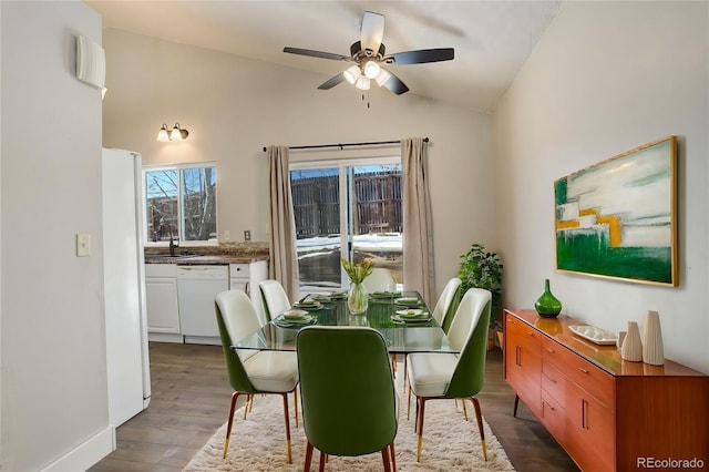 dining area featuring hardwood / wood-style floors, vaulted ceiling, sink, and ceiling fan