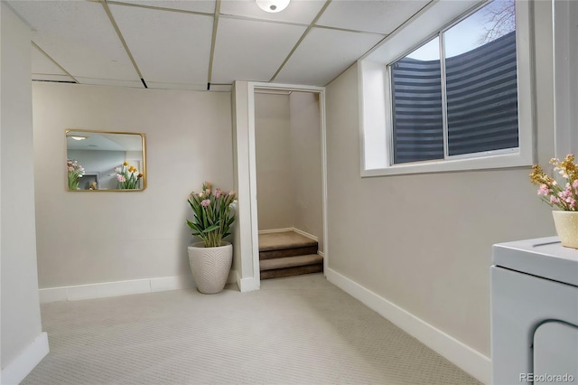 corridor with a paneled ceiling and light colored carpet